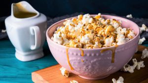 Snack Size Popcorn with salted caramel in pink bowl on wooden board on dark background