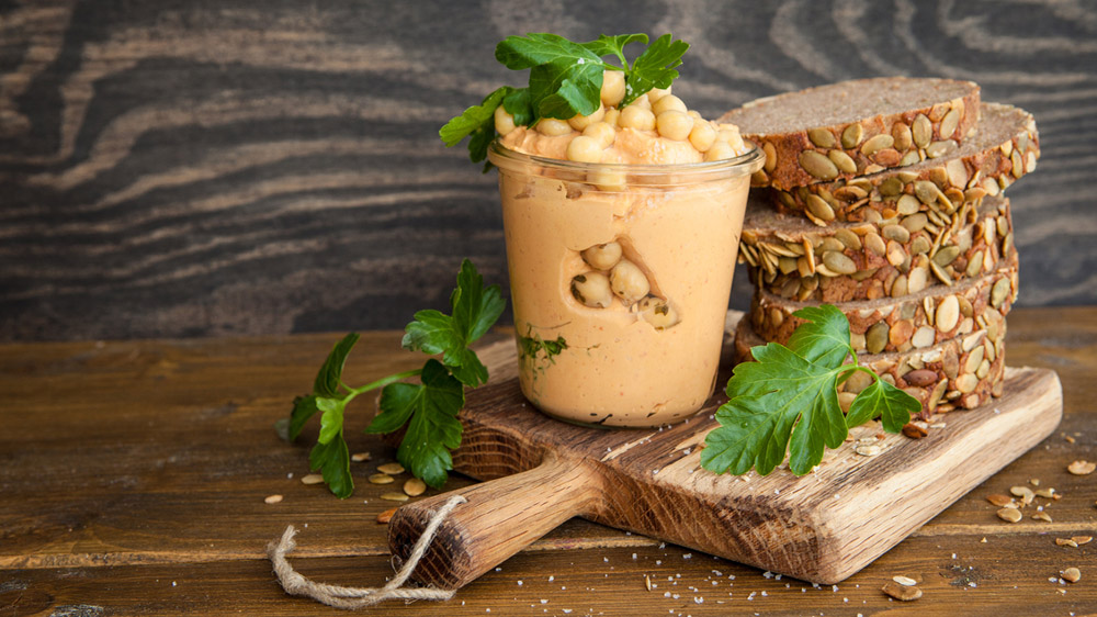 Kichererbsen-Erdnussbutter zum Frühstück neben Brotscheiben