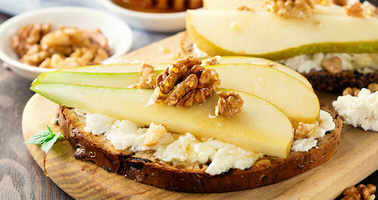 Huettenkaese auf einem Brot mit Birne und Nüssen.