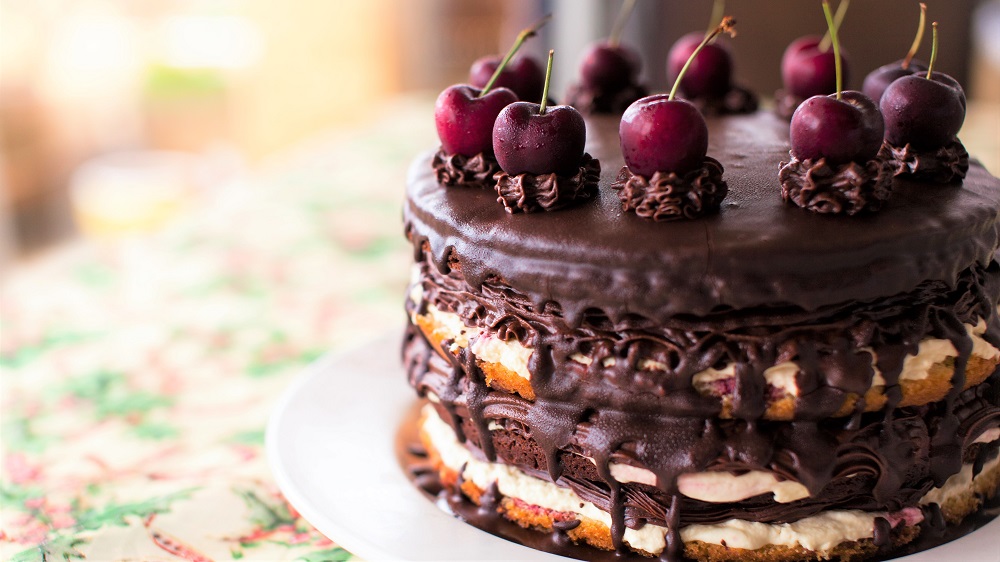 Torte mit hellen und dunklen Waffeln, Sahne, Kuvertüre und Kirschen