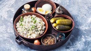 Ein großes Tablett mit Oliver Salat, Gewürzgurken, Eiern und Pfeffer