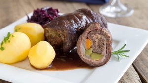 Rouladen mit Kartoffeln und Rotkohl angerichtet auf einem weißen Teller