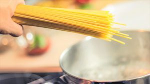 Spaghetti werden in einen Topf gegeben