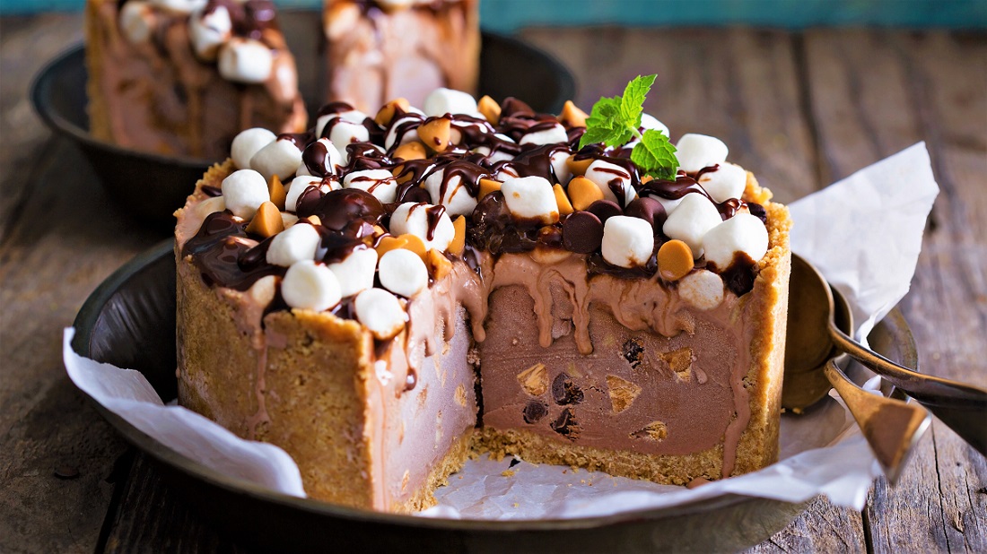 Ice cream cake with marshmallows and peanuts topped with chocolate syrup
