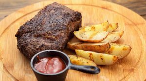airfryer steak veal meat with fried potatoes and tomato sauce on a wooden dish
