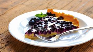 Stück Blaubeer Tarte auf Teller mit Gabel