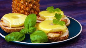schnelle Gerichte, toast hawaii, cheese and pineapple on wooden background with chicken breast