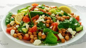 schnelle Gerichte, Chickpeas Salad with cucumber, tomatoes, feta cheese and green mix in a white plate. healthy food