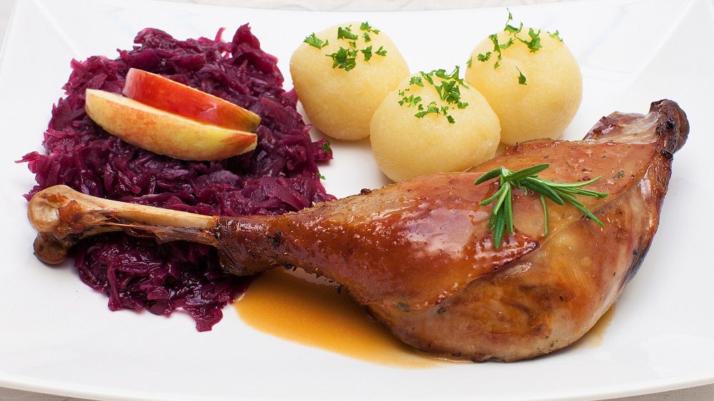 Gänsekeule mit Rotkohl und Klößen - Festtagsessen auf weißer Tischdeck ...