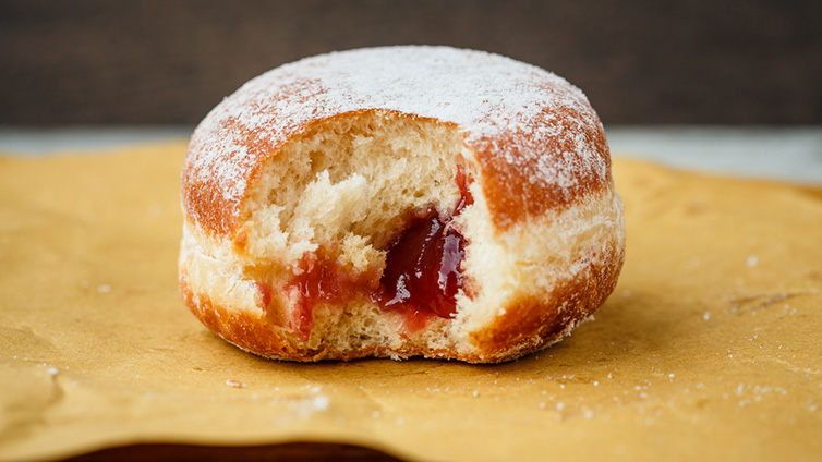 Ein Berliner angebissen mir Marmelade gefüllt