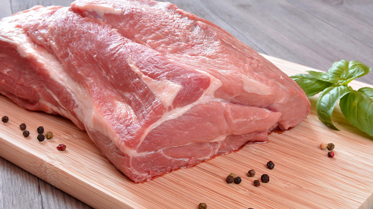 Schweinenackenstück auf Holzbrett für Rollbraten