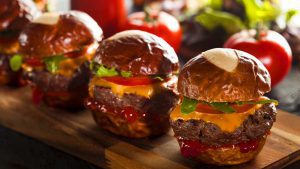 Mini-Burger mit Laugenbrötchen auf Holzbrett