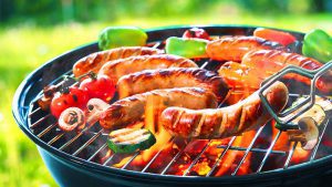 Würstchen und Gemüse auf einem Holzkohlegrill grillen