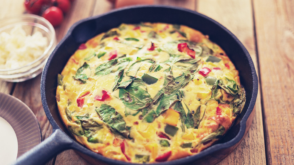 Frittata mit Spinat, Feta und Tomaten in einer Pfanne