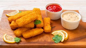 Fischstäbchen auf Holzbrett mit Saucen