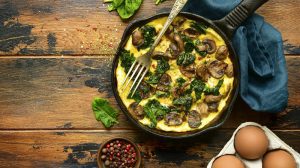 Omelett mit Spinat und Champignons in einer Pfanne von oben