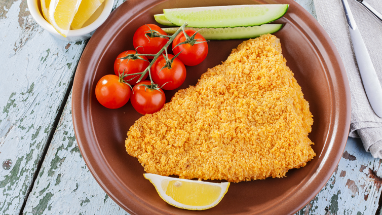 panierter fisch auf teller mit tomaten und gurke komplett