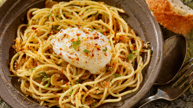 Spaghetti Aglio e Olio mit pochiertem Ei auf Teller