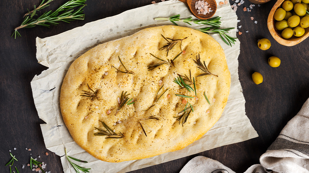 Pizzabrot auf Papier mit Rosmarin und Salz.