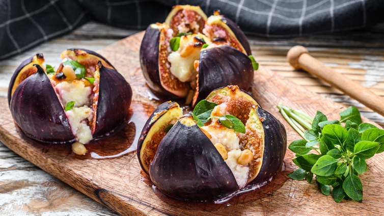 Feigen mit Ziegenkäse und Honig auf einem Holzbrett.