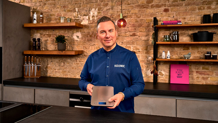 Tim Raue hält die Küchenwaage von KOENIC in der Hand.