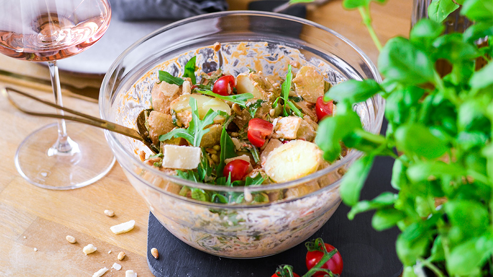 Mediterraner Kartoffelsalat mit Tomaten, Rucola, Pinienkernen und Parmesan in einer Schüssel