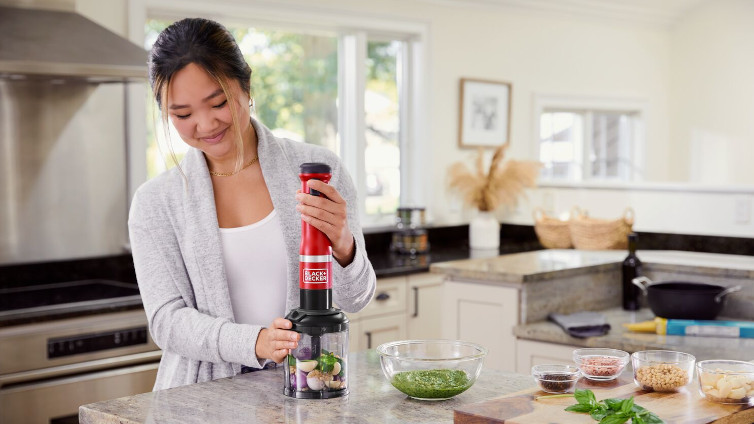 Frau benutzt Black+Decker Kitchen Wand mit dem Zerkleinerer-Aufsatz.