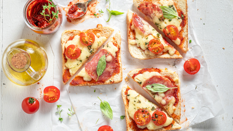 Verschiedene Pizza-Toasts mit Zutaten auf einem Papier.