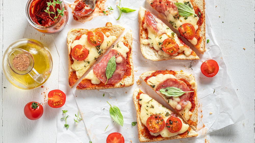 Verschiedene Pizzatoast mit Zutaten auf einem Papier.