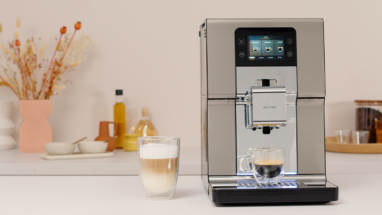 Der Krups Intuition Experience+ Kaffeevollautomat neben vielen Kaffeespezialitäten.