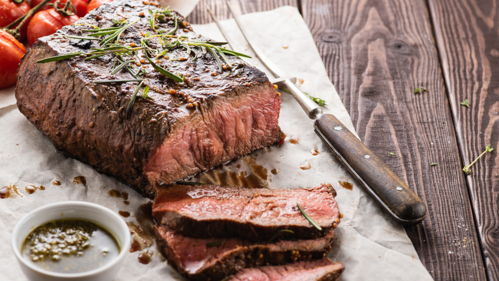 Angeschnittenes Roastbeef liegt auf einem Tisch neben einer Fleischgabel.