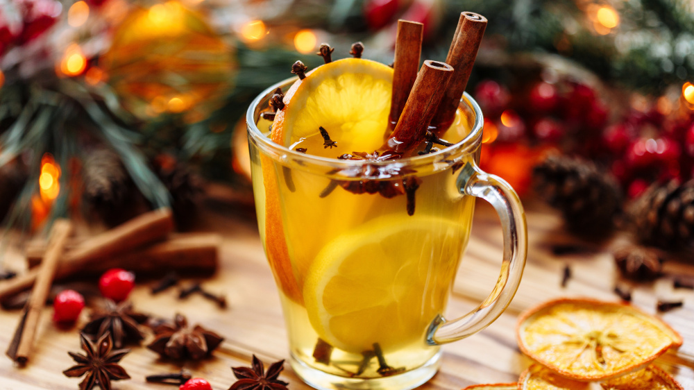 Weißer Glühwein mit Orangenscheiben, Zimtstangen und anderen weihnachtlichen Gewürzen in einem Glas.