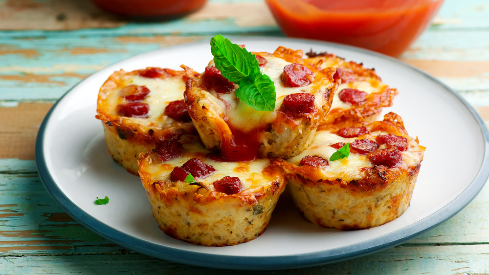 Pizza-Muffins mit Mini-Salami auf einem Teller.