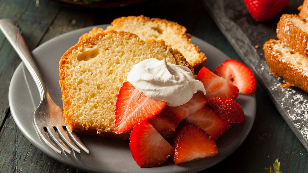 Sandkuchen in Scheiben geschnitten mit Erdbeeren und Sahne.