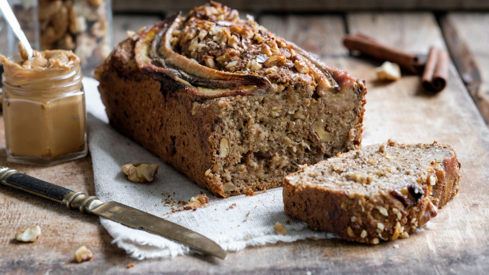 Klassisches Bananenbrot liegt angeschnitten auf einem Tisch.