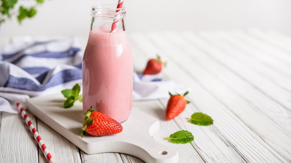 Erdbeer-Milchshake in einer Glasflasche mit Erdbeeren und Strohhalm.
